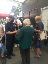 policjantka rozmawia z kobietami na targowisku, rozdaje maseczki