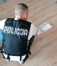 policjant w kamizelce z napisem POLICJA wykonuje czynności z zabezpieczonymi narkotykami