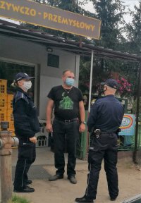 umundurowani policjanci rozmawiają z mężczyzną przed sklepem