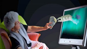 na obrazku widoczna jest starsza kobieta siedząca na fotelu i podająca banknoty dłoni wyłaniającej się z ekranu komputera