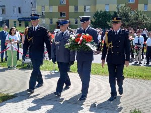 delegacja służb mundurowych, strażak, policjant, służba więzienna, straż miejska składa kwiaty pod pomnikiem