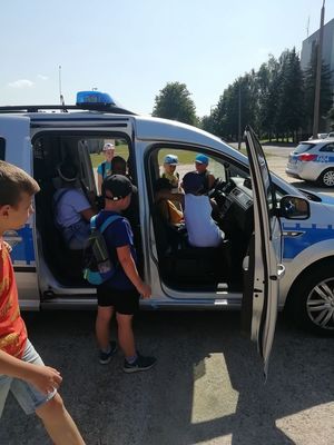 Dzieci wchodzą do radiowozu policyjnego.