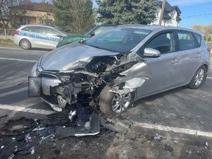Zdjęcie przedstawia uszkodzony pojazd koloru srebrnego znajdującego się na pasie jezdni.
