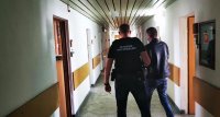 policjant kryminalny prowadzi zatrzymanego korytarzem