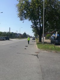 miejsce wypadku policjant wykonuje ogledziny, na ulicy leży rower