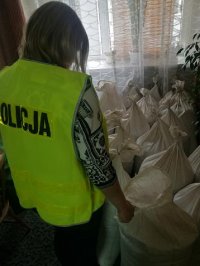 pomieszczenie w którym przechowywane są worki jutowe z krajanką tytoniowa, obok worków stoi policjantka wykonująca czynności