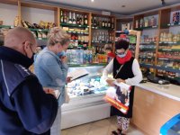 w sklepie stoi policjanta, który zapisuje w  notatnik, członka komisji, sprzedawca trzyma palakat