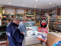 w sklepie stoi policjant który robi zapiski w notesie, sprzedawca trzyma rozwinięty plakat