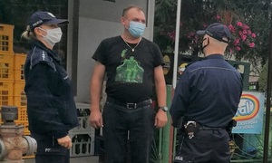 umundurowani policjanci rozmawiają z mężczyzną przed sklepem