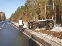 policjanci podczas oględzin śmiertelnego wypadku drogowego. na zdjęciu policyjny radiowóz i umundurowany policjant, w tle pojazd w rowie