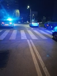 na ulicy widać oznakowane radiowozy , po prawej stronie pasa drogowego stoi motocykl