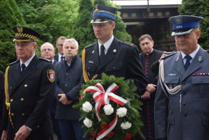 DELEGACJA SŁUŻB MUNDUROWYCH NA UROCZYSTOŚCI, UMUNDUROWANY STRAŻAK TRZYMA KWIATY, OBOK NIEGO UMUNDUROWANY POLICJANT, STRAŻNIK MIEJSKI,