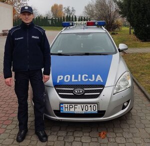 przed radiowozem stoi umundurowany policjant