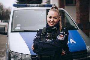 Przed radiowozem stoi umundurowana policjantka.