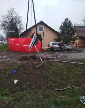 miejsce wypadku śmiertelnego rozbity samochód z uderzył w ogrodzenie posesji,  z lewej strony czerwony parawan