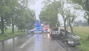 miejsce wypadku drogowego, w rowie leży uszkodzony  samochód koloru szarego w tle oznakowany radiowóz, i samochód straży pożarnej