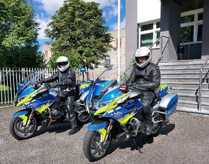 przed budynkiem komendy umundurowani policjanci siedzą na oznakowanych nowych motocyklach