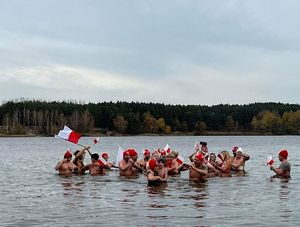 kilkanaście osób stoi zanurzonych w wodzie