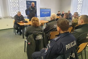 w pomieszczeniu siedzą umundurowani funkcjonariusze  przed nimi stoi dyrektor