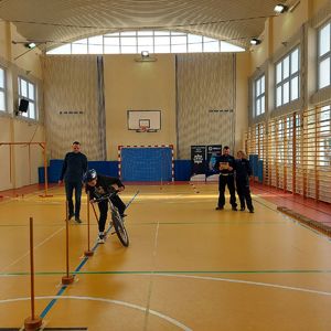 Eliminacje Powiatowe Ogólnopolskiego Turnieju Bezpieczeństwa w Ruchu Drogowym na sali gimnastycznej szkoły podstawowej -  dzieci pokonują tor przeszkód.