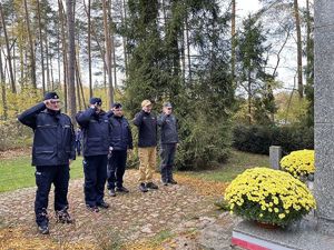 Przed pomnikiem powstańców umundurowani policjanci i przedstawiciele służb mundurowych oddają honor.