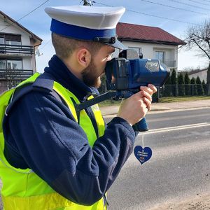 Umundurowany policjant mierzy prędkość.