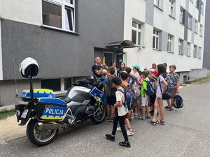 Na zdjęciu widać stojące motocykle służbowe policyjne, funkcjonariusza policji oraz dzieci.