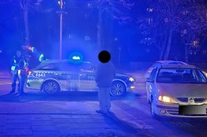 Miejsce zdarzenia drogowego na terenie miasta , pora wieczorna, widać policjantów, oznakowany radiowóz, osobowy samochód.