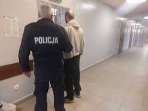 W policyjnym areszcie umundurowany policjant  prowadzi zatrzymanego.