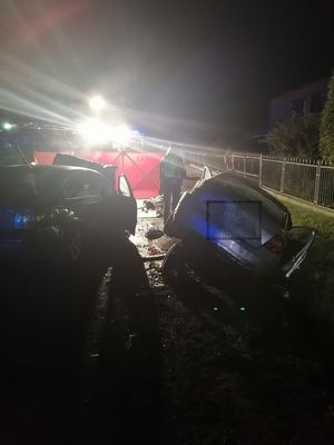 Miejsce wypadku drogowego, na miejscu pracują służby ratunkowe, policja, straż pożarna, widać uszkodzone pojazdy biorące udział w zdarzeniu.