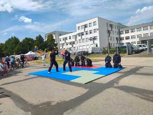 Piknik przed budynkiem komendy, rozstawione są namioty wystawców, pojazdy służb mundurowych, osoby odwiedzają stoiska.