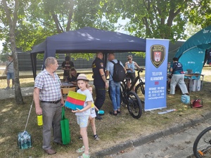 Piknik przed budynkiem komendy, rozstawione są namioty wystawców, pojazdy służb mundurowych, osoby odwiedzają stoiska.