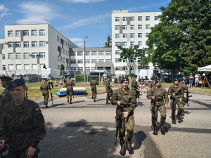 Piknik przed budynkiem komendy, rozstawione są namioty wystawców, pojazdy służb mundurowych, osoby odwiedzają stoiska.