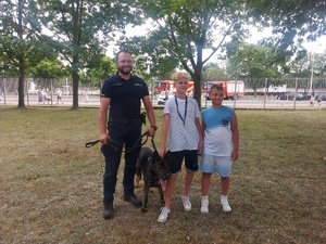 Piknik przed budynkiem komendy, rozstawione są namioty wystawców, pojazdy służb mundurowych, osoby odwiedzają stoiska.