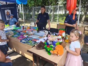 Piknik przed budynkiem komendy, rozstawione są namioty wystawców, pojazdy służb mundurowych, osoby odwiedzają stoiska.