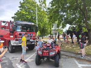 Piknik przed budynkiem komendy, rozstawione są namioty wystawców, pojazdy służb mundurowych, osoby odwiedzają stoiska.