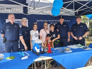 Piknik przed budynkiem komendy, rozstawione są namioty wystawców, pojazdy służb mundurowych, osoby odwiedzają stoiska.