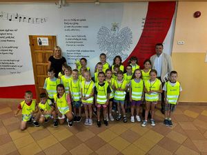 Na zdjęciu  widać dzieci  oraz osoby dorosłe ubrane w żółte kamizeli i trzymające żółte odblaskowe worki.