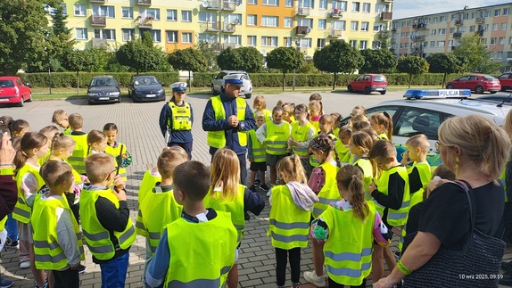 Spotkanie  przed szkołą policjantów i pracowników WORD - u z dziećmi, rozdawanie kamizelek odblaskowych i nauka  przechodzenia przez pasy.