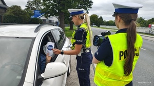 Umundurowane policjantki kontrolują pojazdy i wręczają kierowcom ulotki w ramach kampanii &quot;Mistrzu zwolnij&quot;