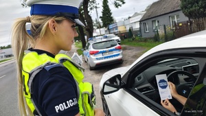 Umundurowane policjantki kontrolują pojazdy i wręczają kierowcom ulotki w ramach kampanii &quot;Mistrzu zwolnij&quot;