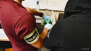 Technik kryminalistyki wykonuje odciski palców zatrzymanej kobiecie.