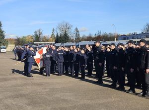 Na zdjęciu widać stojących na placu funkcjonariuszy, którzy stoją przed sztandarem.