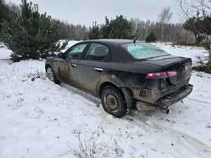 W komplecie leśnym stoi porzucony samochód koloru czarnego.