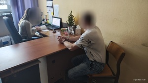 W pomieszczeniu służbowym policjantka przesłuchuje zatrzymanego mężczyznę.