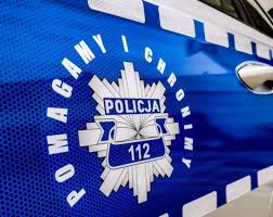 Boczne drzwi policyjnego radiowozu na nim logo policji  wokół napis Pomagamy i Chronimy.