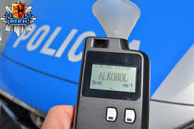 Alkomat na tle maski policyjnego radiowozu, w lewym górnym rogu logo Komendy Powiatowe Policji w Sieradzu.