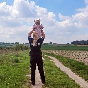 Umundurowana policjantka trzyma na rękach dziewczynkę.
