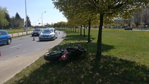 miejsce wypadku.widać drogę na której stoi radiowóz, na poboczu lezy motocykl i kask